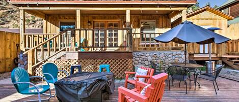A wooden deck with outdoor furniture, a covered barbecue area, and a stone wall.