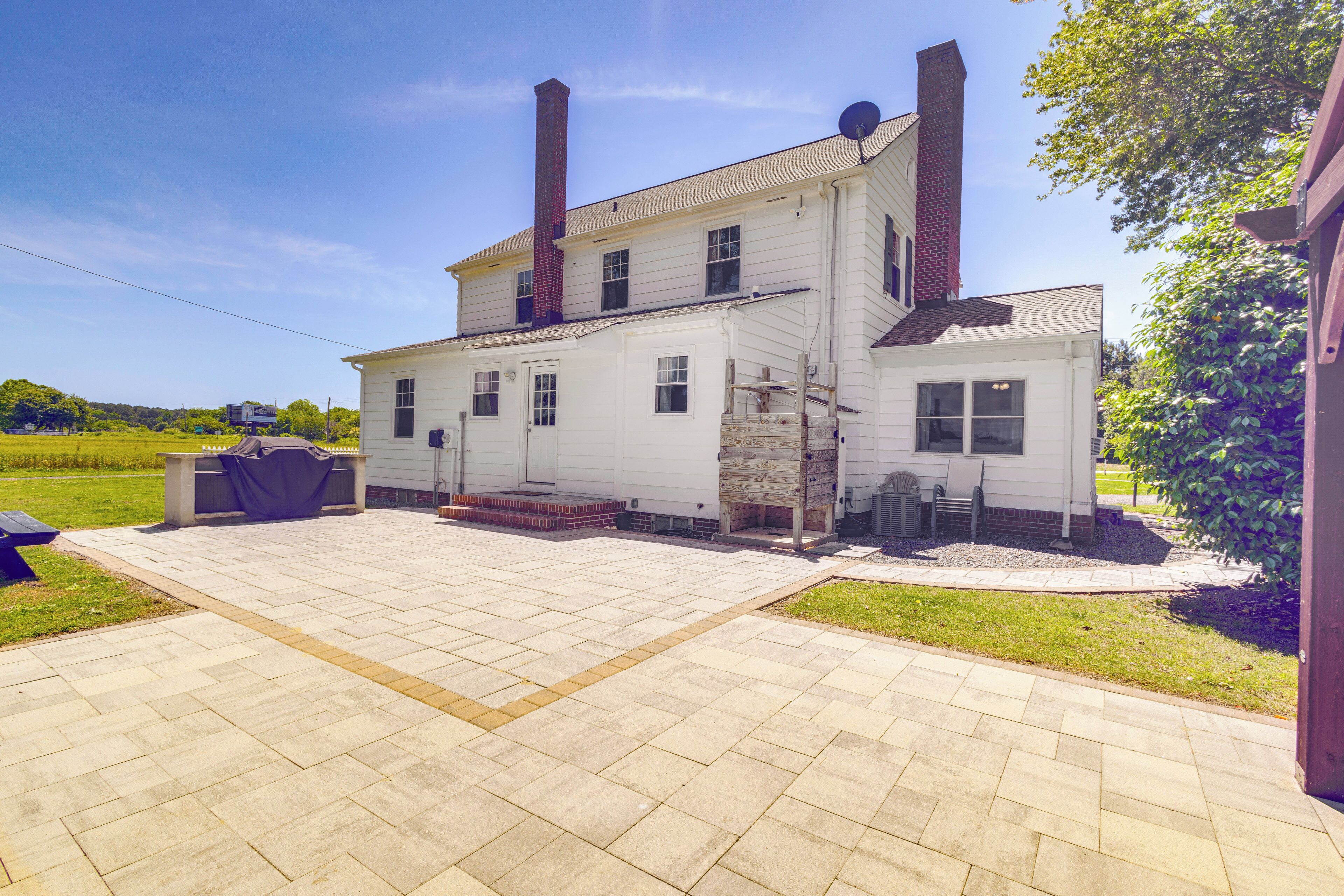 A two-story house with a paved patio, a chimney, and a satellite dish.
