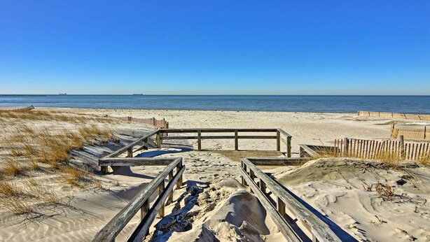 Une plage de sable avec des allées en bois et une clôture en bois.
