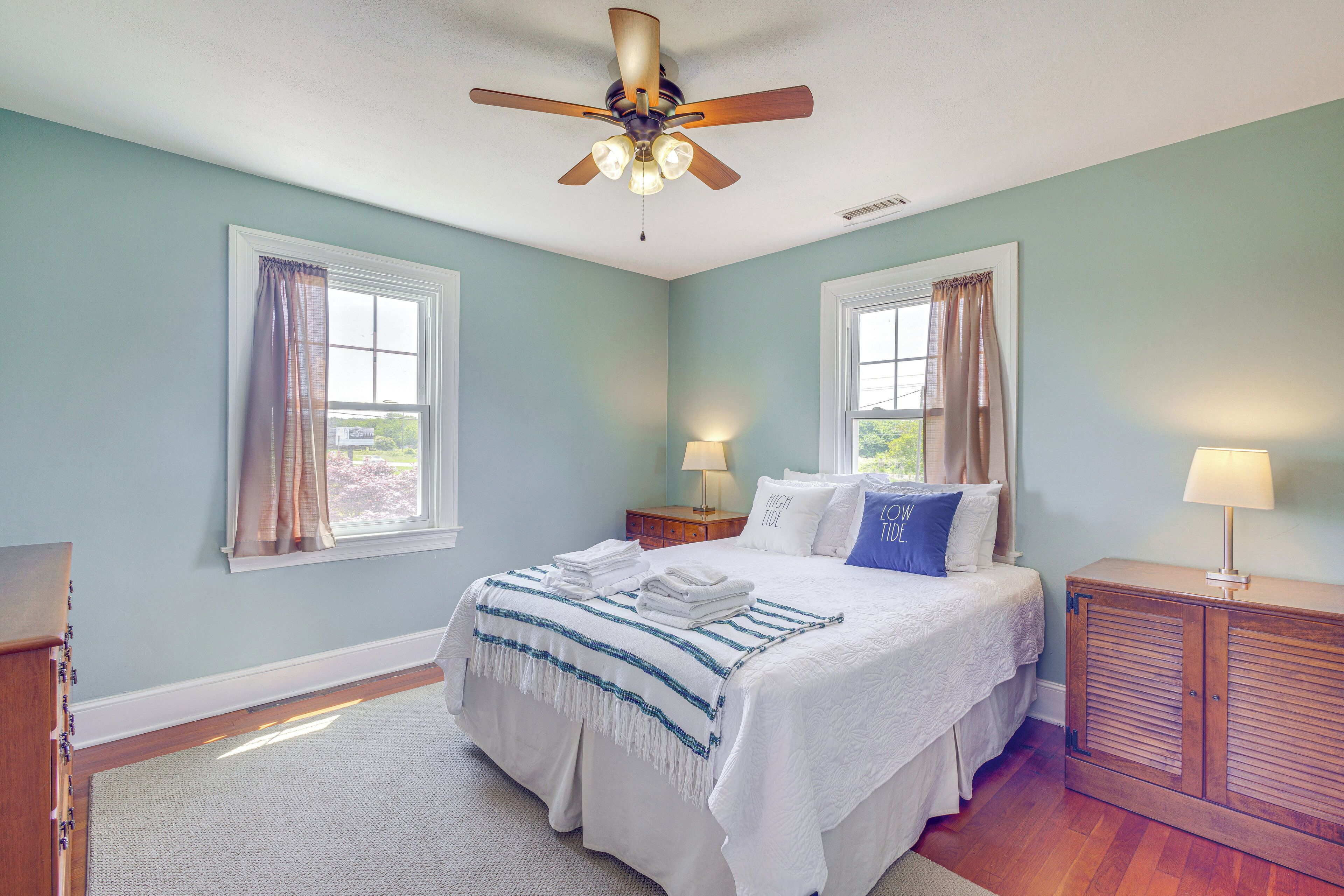 A bedroom with a bed, nightstands, a ceiling fan, and a window with curtains.