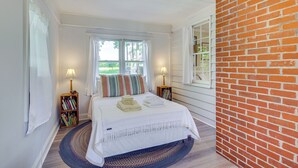 Une chambre à coucher avec un lit, deux lampes de chevet, une bibliothèque et une vue sur l’extérieur.
