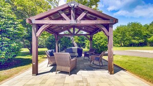 Un patio couvert aménagé avec du mobilier d’extérieur et un barbecue.