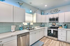 A modern kitchen with white cabinets, a stainless steel dishwasher, a microwave, and an oven. - Gulf-view Home w/ Dog Run in Surfside Beach! (Freeport)