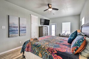 A bedroom with a large bed, a ceiling fan, a TV, and artwork on the walls. - Gulf-view Home w/ Dog Run in Surfside Beach! (Freeport)