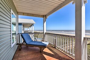 A wooden deck with a blue lounge chair, a covered area with a railing, and a view of the ocean. - Gulf-view Home w/ Dog Run in Surfside Beach! (Freeport)