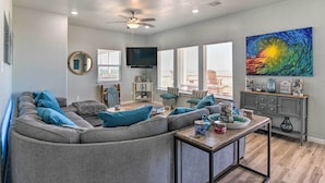 A modern living room with a sectional sofa, a coffee table, and a television. - Gulf-view Home w/ Dog Run in Surfside Beach! (Freeport)