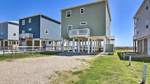 A row of beach houses with balconies, a gravel driveway, and a grassy area. - Gulf-view Home w/ Dog Run in Surfside Beach! (Freeport)