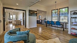 A spacious living area with a curved blue sofa, a wooden coffee table, and a large window with a view of the outdoors.