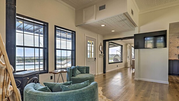 A spacious living room with large windows, a fireplace, and a modern kitchen area.
