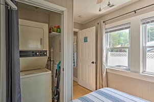 Un dormitorio pequeño con cama, lavadora y puerta que da a otra habitación.