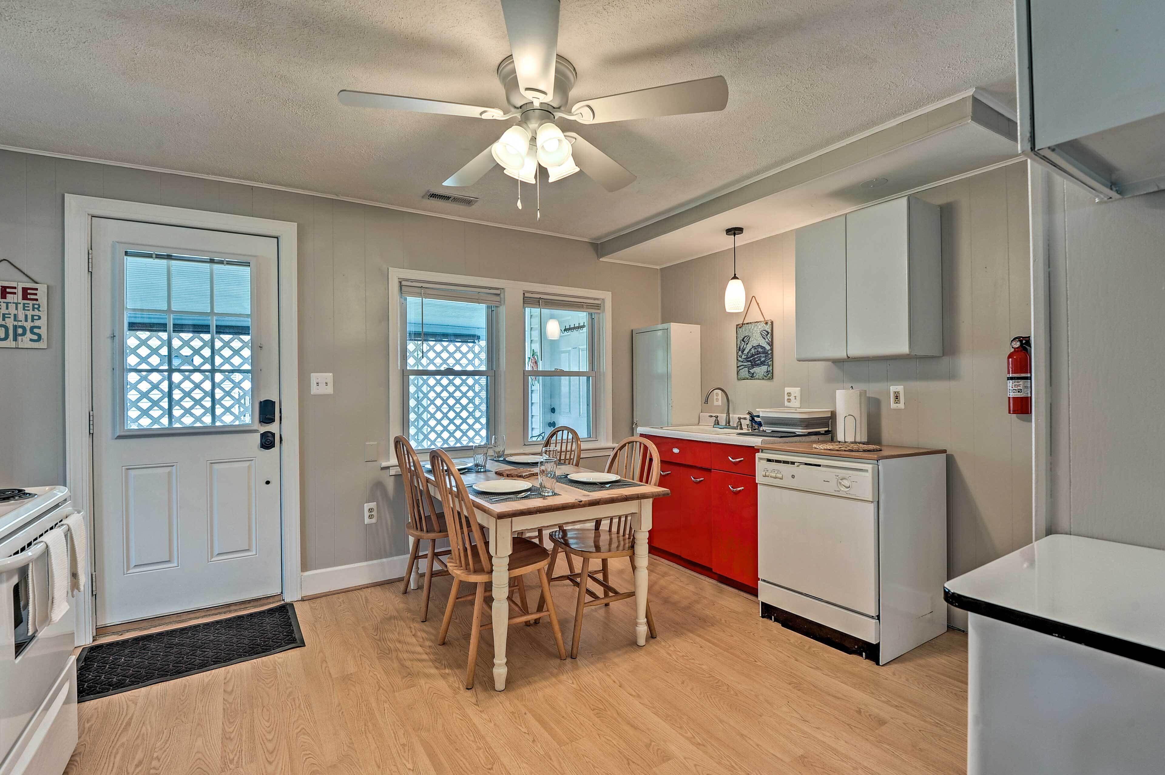 A kitchen with a dining table, chairs, a ceiling fan, and a red cabinet.