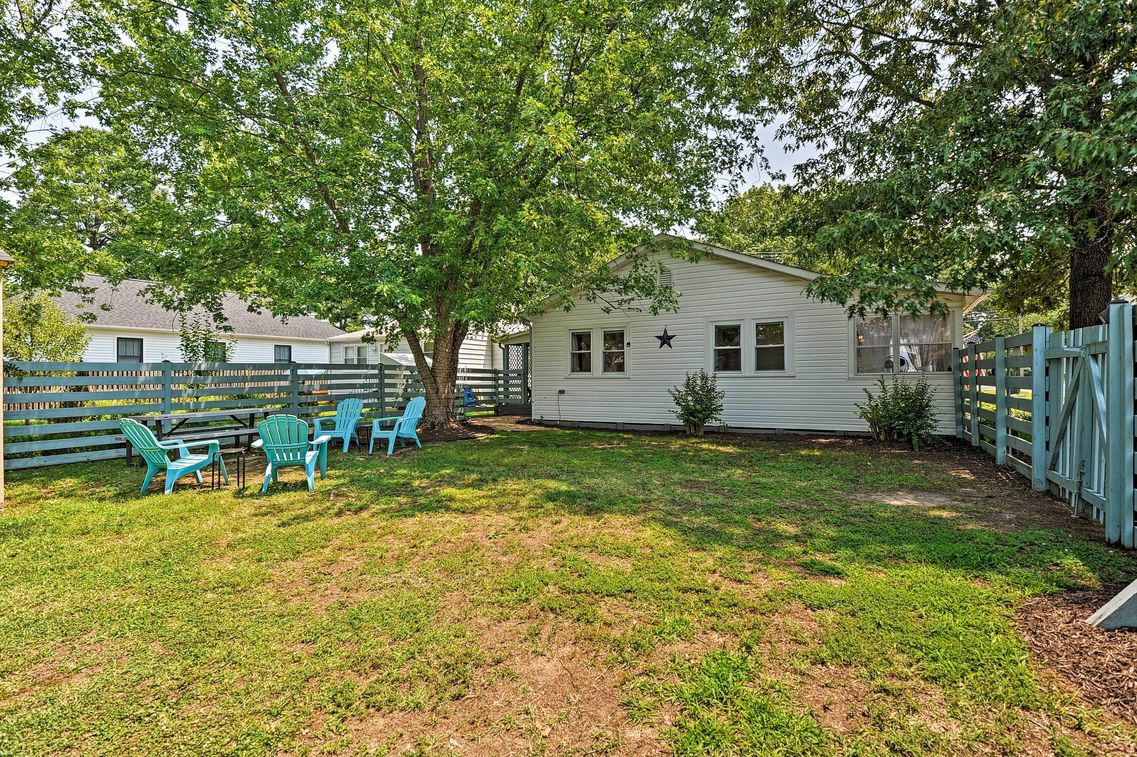 A house with a fenced yard, a tree, and a small garden area.