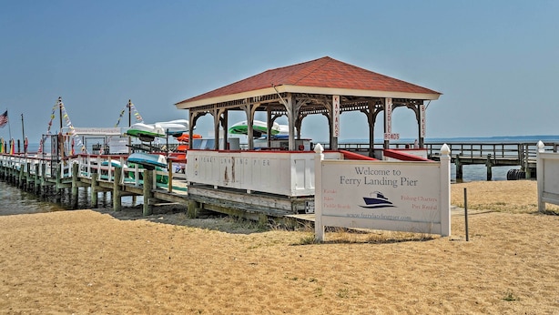 Un muelle con zona de estar cubierta y un cartel que indica que es muelle de atraque de transbordador, que ofrece alquiler de kayaks, bicicletas, tablas de paddle surf y alquiler de muelles.