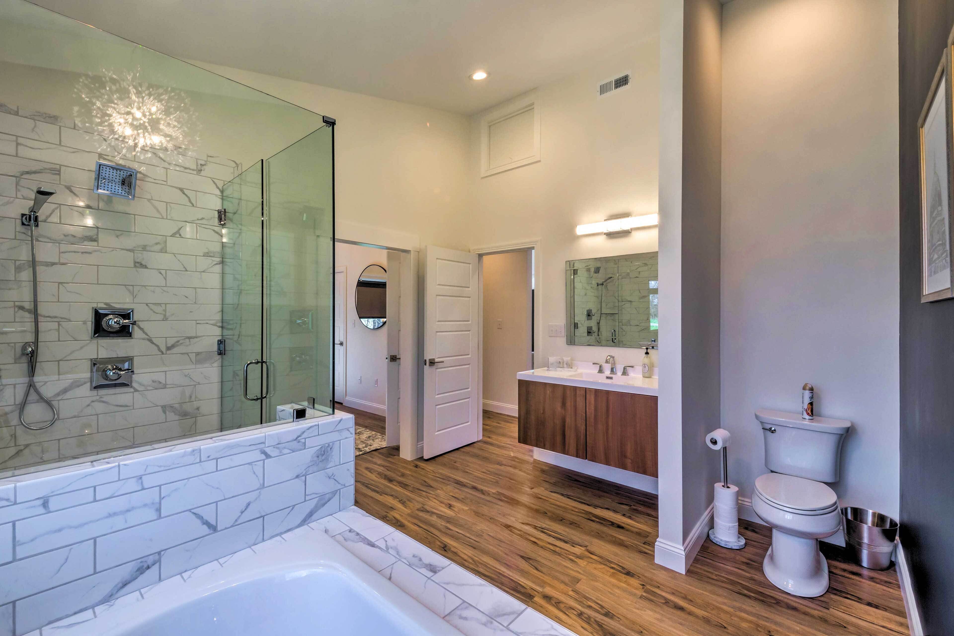 Un baño moderno con ducha de vidrio, una bañera grande y un tocador con espejo.
