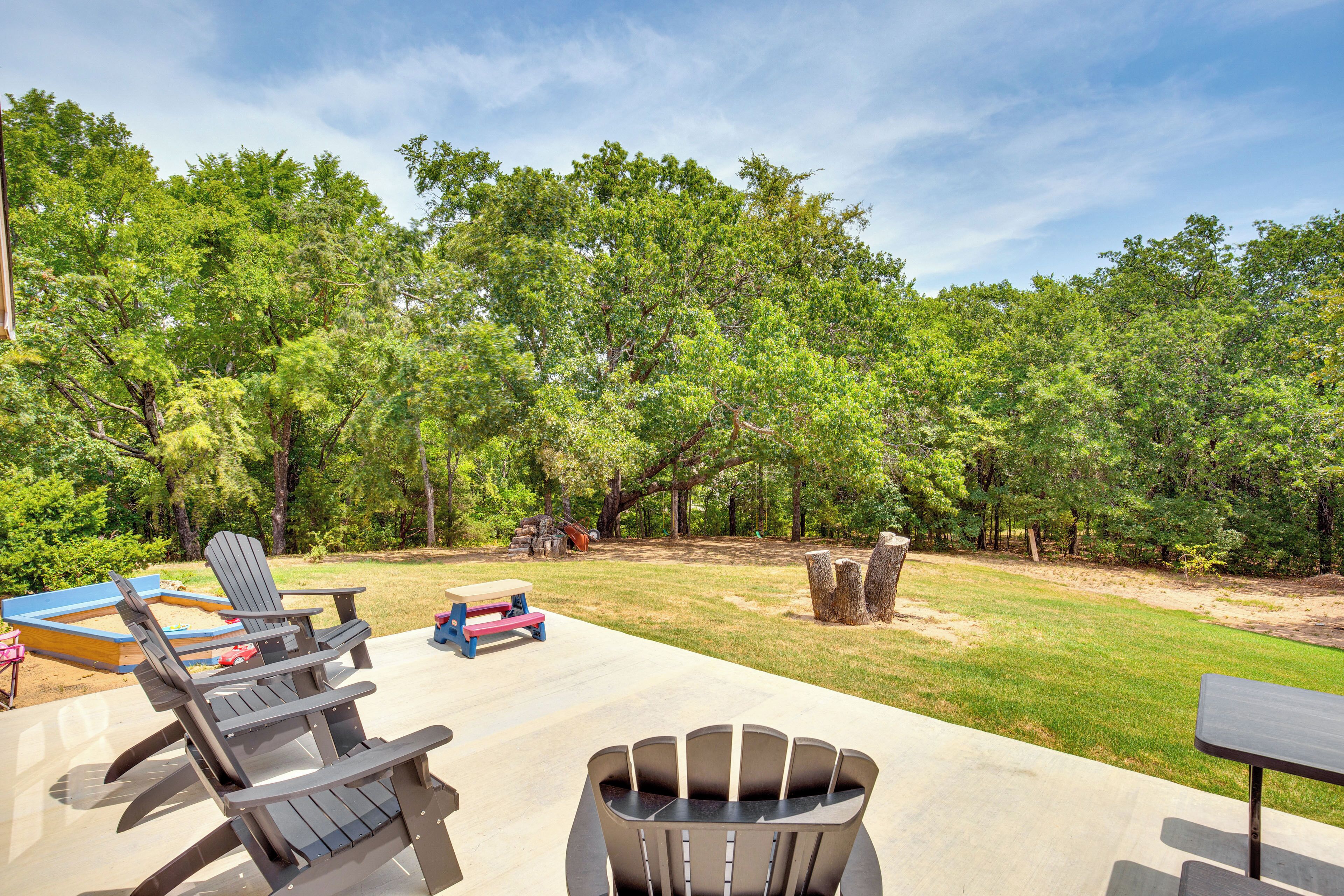 An outdoor patio with Adirondack chairs, a picnic table, and a fire pit.