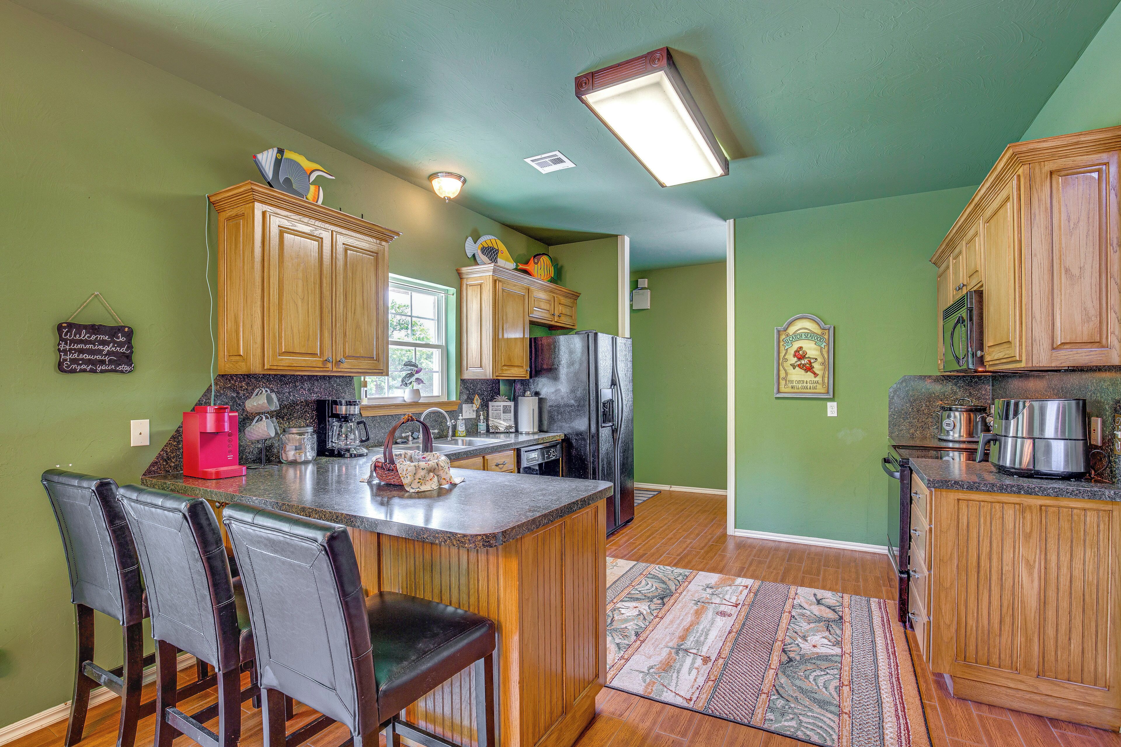 A kitchen with wooden cabinets, a central island with bar stools, a refrigerator, and a coffee maker.