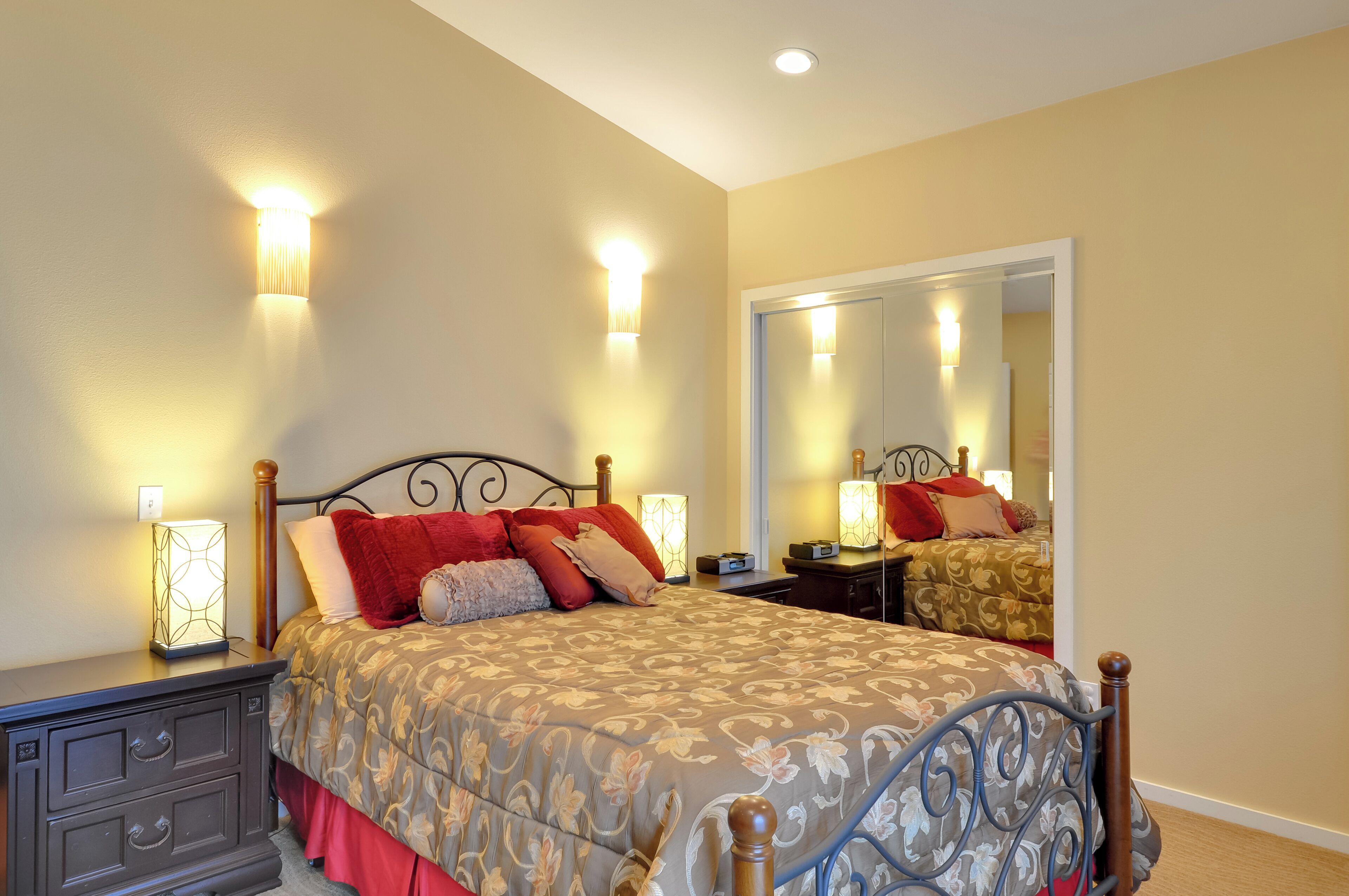 A bedroom with a bed, bedside tables, a dresser, and a mirror.