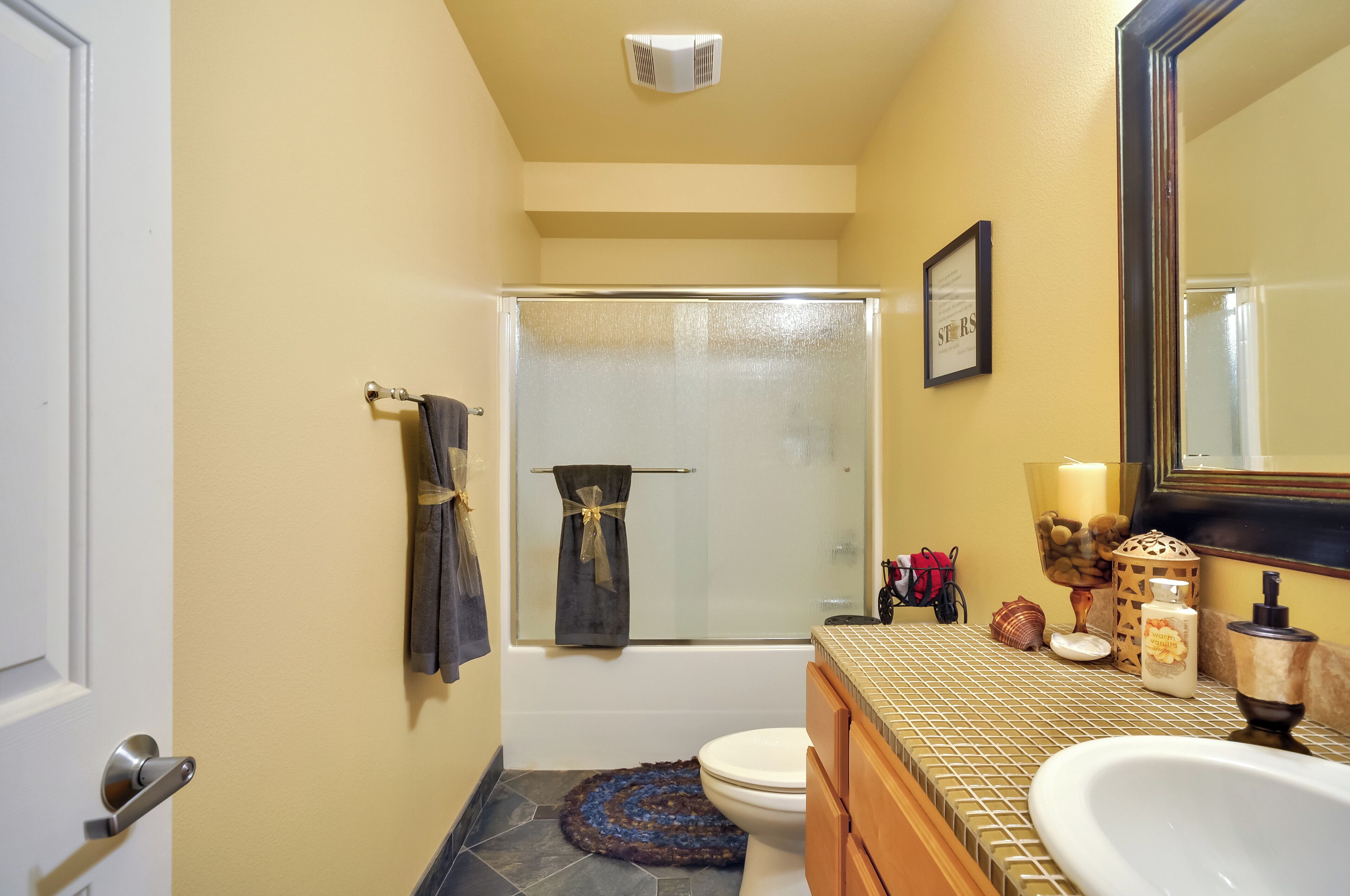 Un baño con cabina de ducha de vidrio, inodoro, lavamanos con espejo y un perchero para toallas.