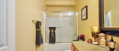 Un baño con cabina de ducha de vidrio, inodoro, lavamanos con espejo y un perchero para toallas.