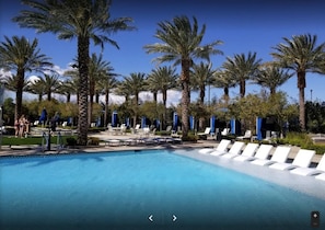A pool area with lounge chairs and palm trees.
