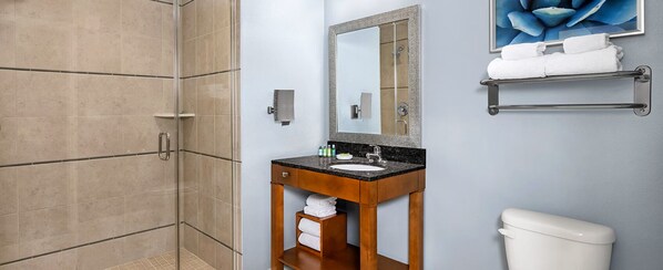 A bathroom with a shower, sink, mirror, and toilet.