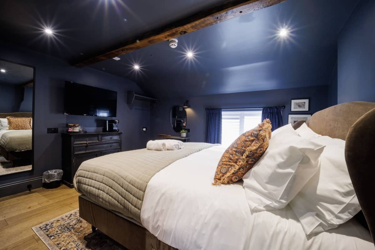 Ein Schlafzimmer mit einem großen Bett, einem Schminktisch, einem Spiegel und einem Fenster mit Vorhängen.