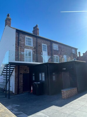 A two-story brick building with a flat roof and a covered outdoor area with a staircase. - The Silk Rooms at Freemasons Inn (Knutsford)