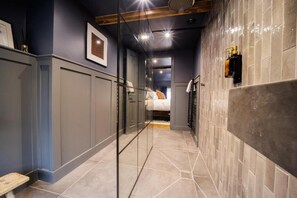 A narrow hallway with a bench, a glass partition, and a bed in the distance. - The Silk Rooms at Freemasons Inn (Knutsford)