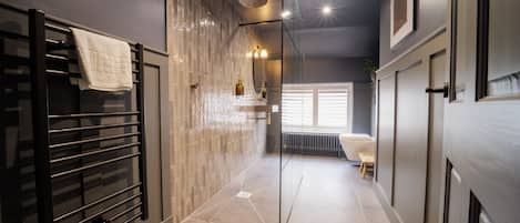 Un baño moderno con cabina de ducha de vidrio, un perchero y un radiador.