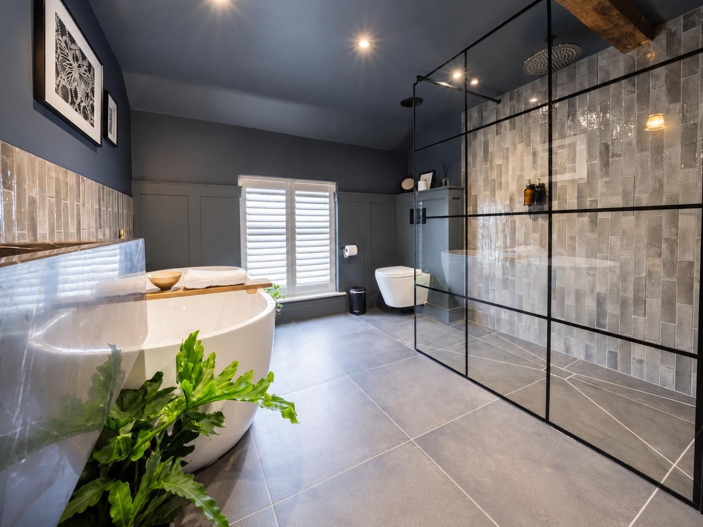 Un baño moderno con una bañera independiente, un box de ducha de cristal y un ventanal grande.