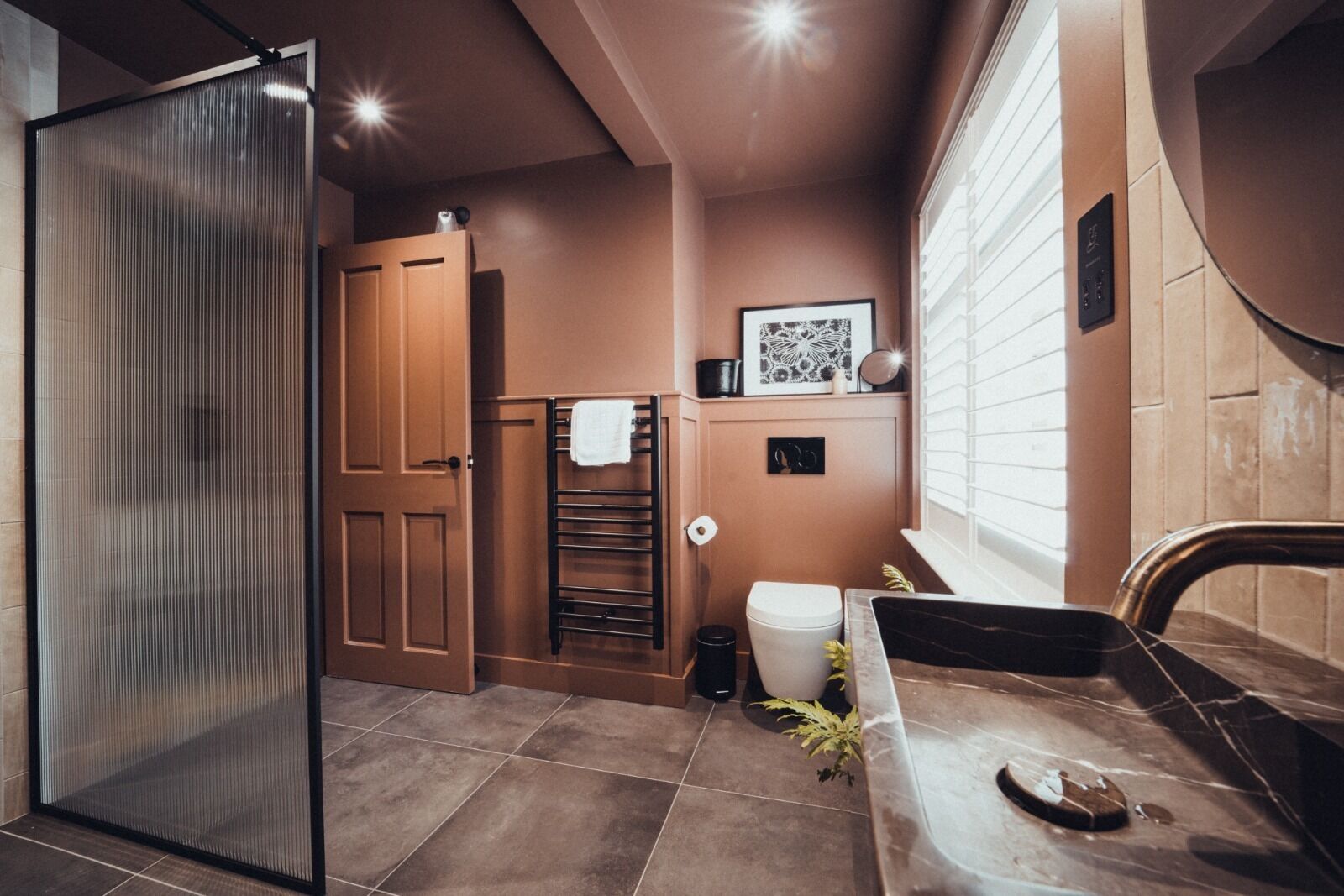 A bathroom with a toilet, sink, towel rack, and a shower area.