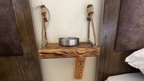 A small, compact room with two beds, a metal bowl on a shelf, and a wall-mounted electrical outlet. - Nabati Hostel  (At-Taybeh)
