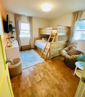 A cozy room with a bunk bed, a small desk, a chair, and a window with curtains.