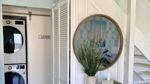A laundry room with two washing machines, a mirror, and a small table with decorative items. - Amazing Beach house Steps from the Surf
"Nautical Endeavors" (Rodanthe)