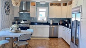 A modern kitchen with white cabinets, a stainless steel range, and a dishwasher. - Amazing Beach house Steps from the Surf
"Nautical Endeavors" (Rodanthe)