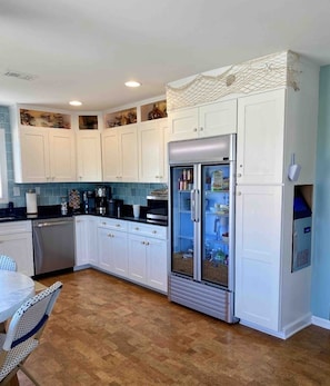A modern kitchen with white cabinets, a stainless steel refrigerator, and a coffee maker.