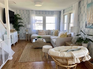 A cozy living room with a sofa, a coffee table, a side table, and a wicker chair.