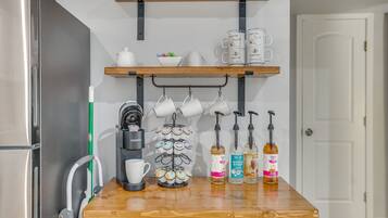 Eine Küchenarbeitsplatte mit einer Kaffeemaschine, Tassen und Getränkespendern.
