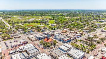 Vista aérea de un pueblo con una plaza central, edificios circundantes y zonas verdes.