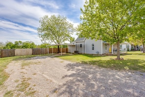 A residential property with a covered patio, a fenced yard, and a house with a front porch. - The Hive · 3BR · Pet Friendly · Near Tarleton (Stephenville)