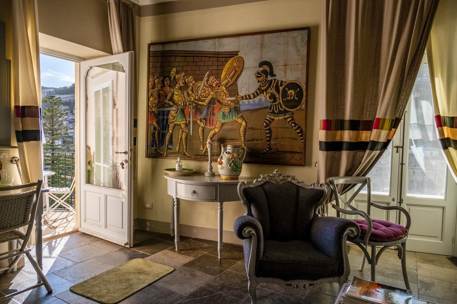 Una stanza con un grande quadro, un tavolo con un vaso, una sedia e una vista attraverso una porta.