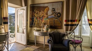 A room with a large painting, a table with a vase, a chair, and a view through a door. - Jasmine Luxury House with terrace (Modica)