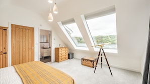 A bedroom with a skylight, wooden wardrobe, a bed with a plaid blanket, a dresser, and a telescope. - Beach View (Ilfracombe)