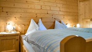 Une chambre dans un chalet en bois, avec deux lits, chacun doté de draps à rayures et de lampes de chevet.
