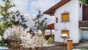 Un chalet doté d’une terrasse en bois, entouré d’arbres couverts de neige, avec une vue imprenable sur les montagnes.