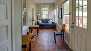 A room with a wooden floor, a blue sofa, a wooden table, and a chair.
