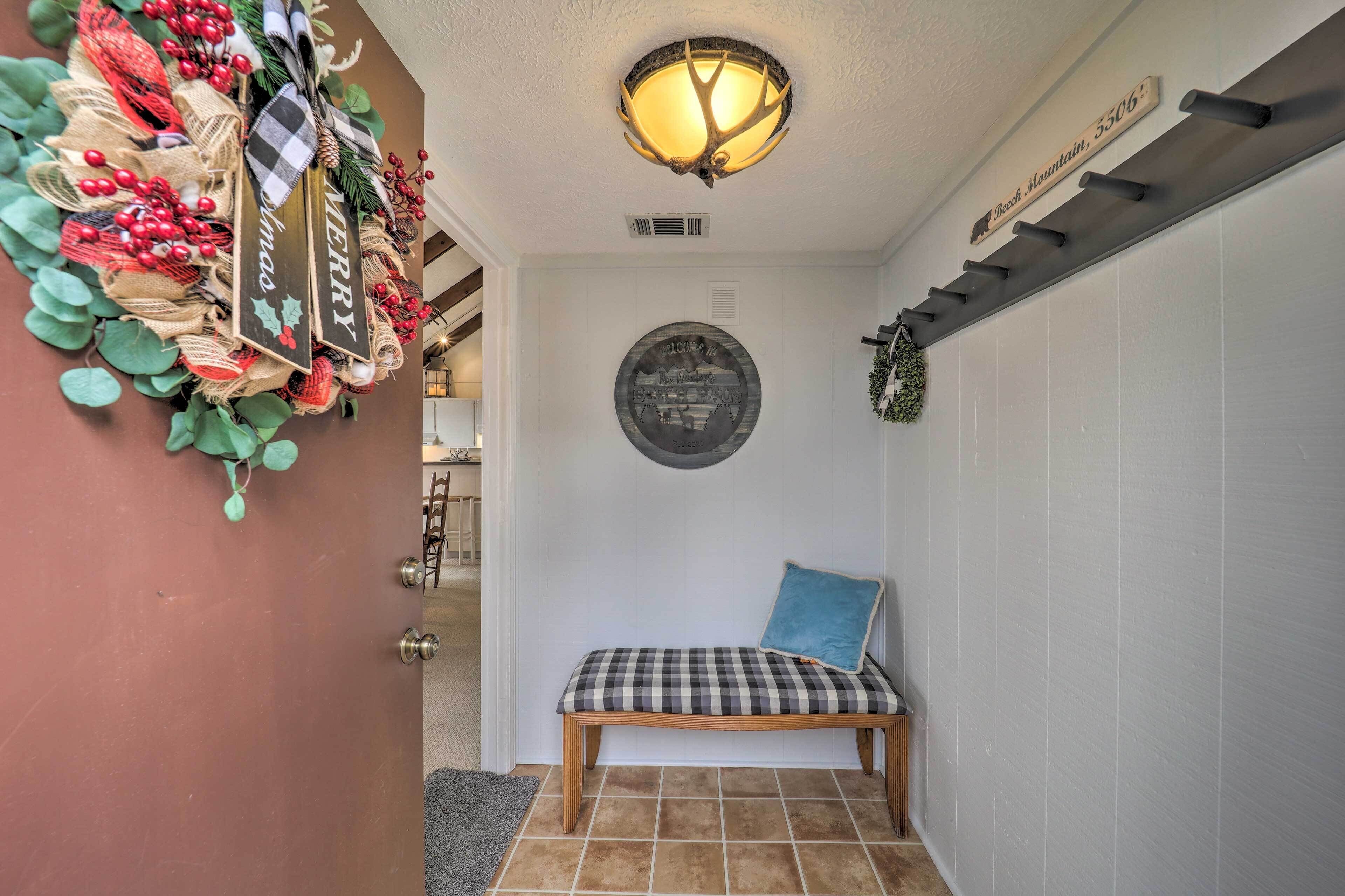 A hallway with a bench, a wall-mounted sign, and a decorative wreath.