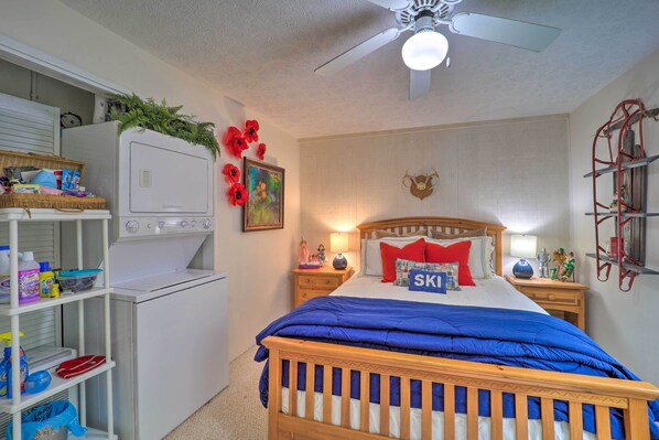 A bedroom with a bed, a ceiling fan, a washing machine, and a shelf with laundry supplies. - Beautiful Beech Mountain Condo w/ Private Balcony! (Banner Elk)