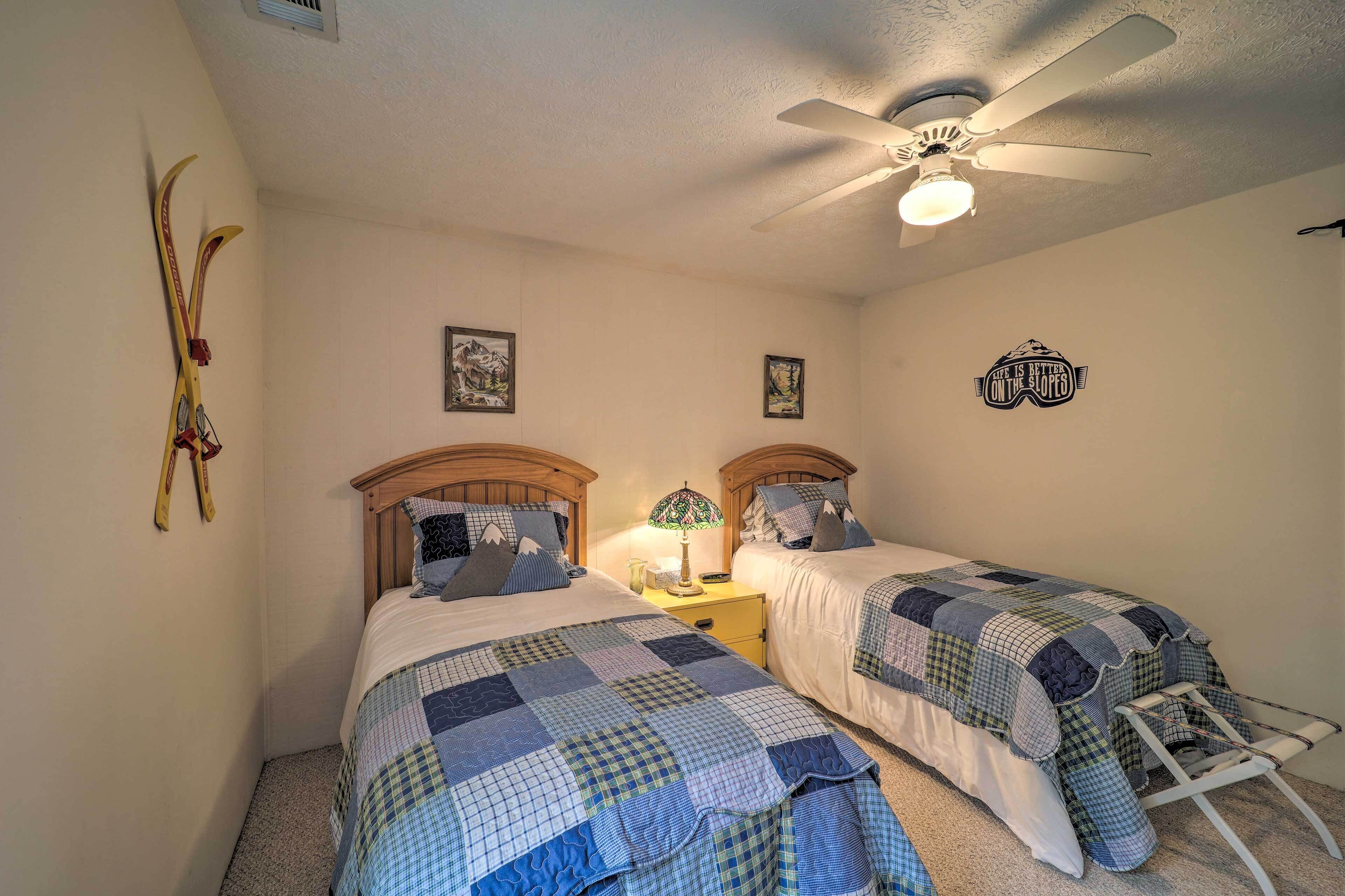 A bedroom with two beds, a ceiling fan, and wall decorations.