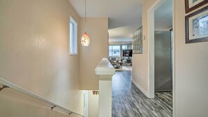 A modern kitchen with stainless steel appliances, a dining area with a white table and chairs, and a staircase with a white railing leading to an upper level. - Walk to Downtown & Coast Trail: Condo in Anchorage (Anchorage)